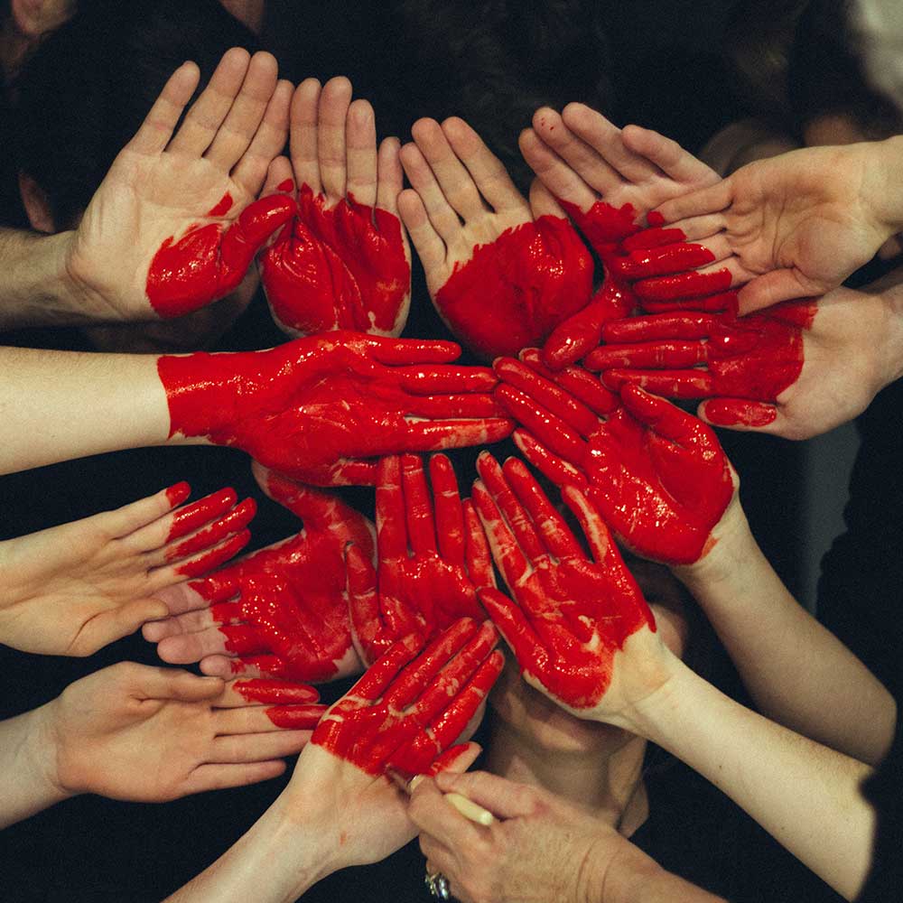 team hands gathered together illustrating a red heart