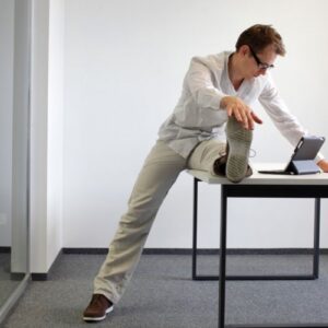 Man watching his laptop while performing stretches on the table
