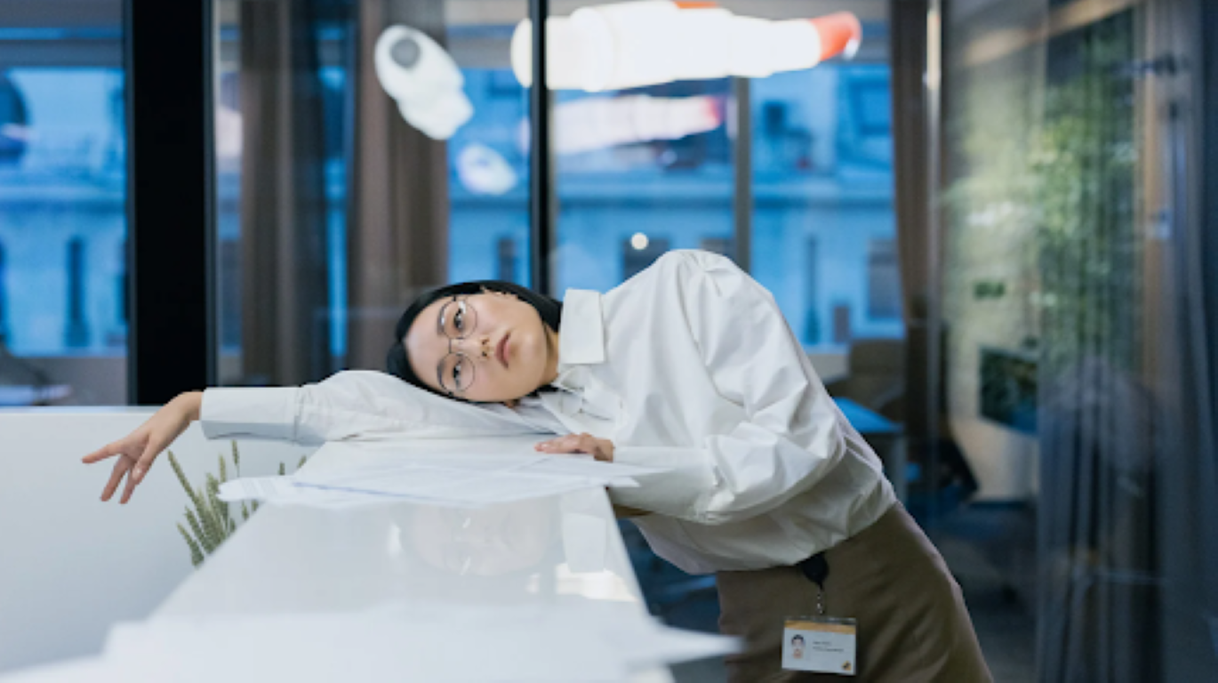 Employee slumped over a desk, showing signs of summer disengagement—an opportunity for leaders to create connection through neuroscience-based strategies.