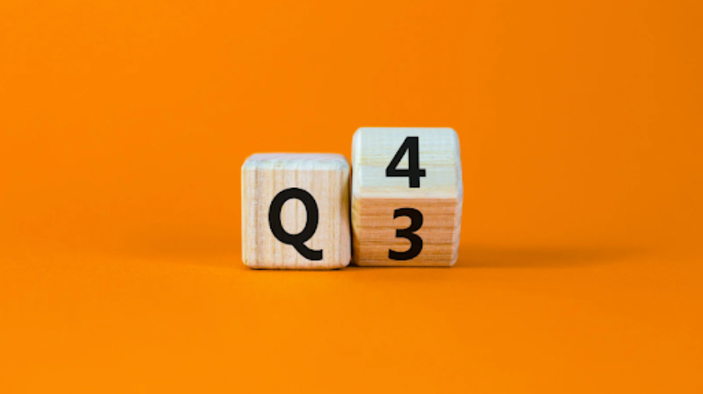 Two wooden blocks labeled “Q3” and “Q4” on a bold orange background, symbolizing the shift from one business quarter to the next and the importance of early preparation.