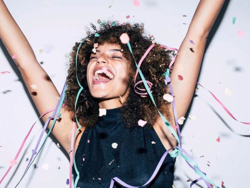 Person celebrating with arms raised and confetti falling, symbolizing momentum, follow-through, and positive habit change through brain training.