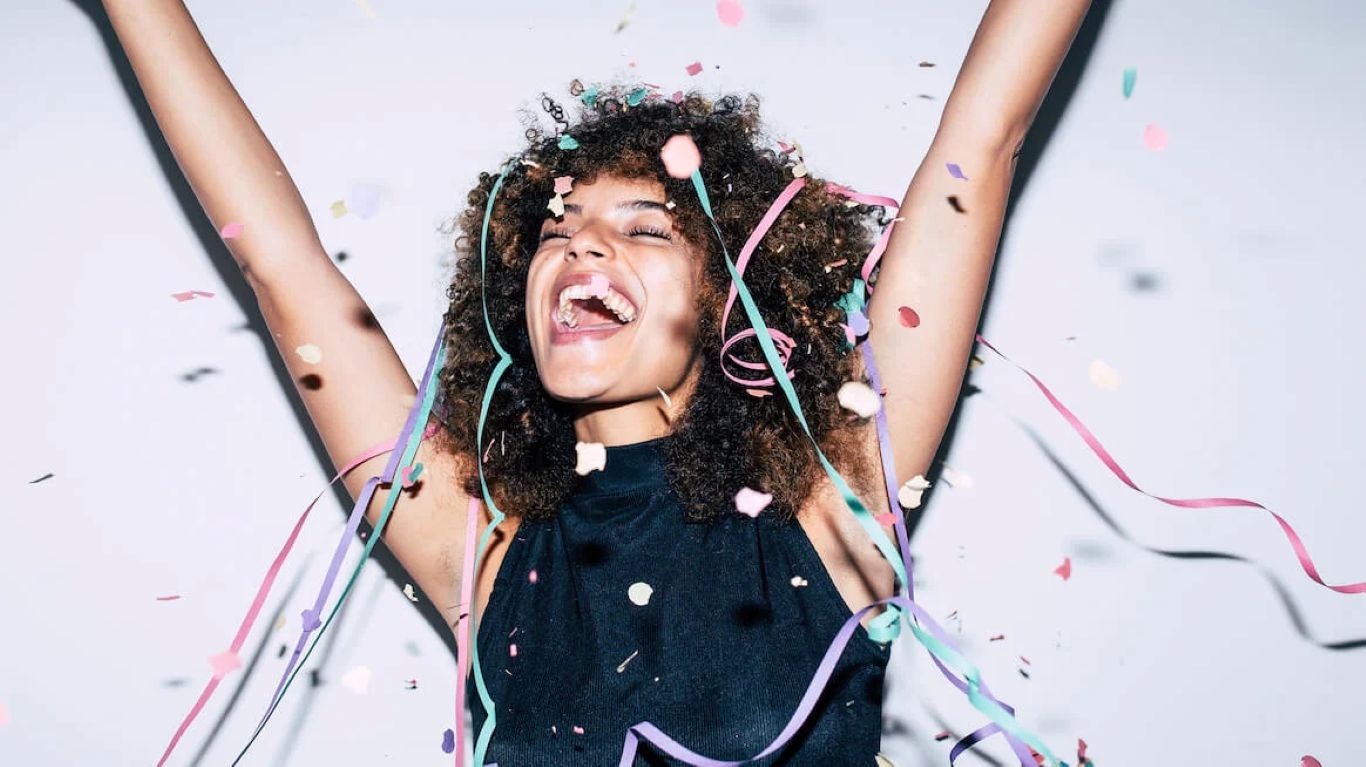 Person celebrating with arms raised and confetti falling, symbolizing momentum, follow-through, and positive habit change through brain training.