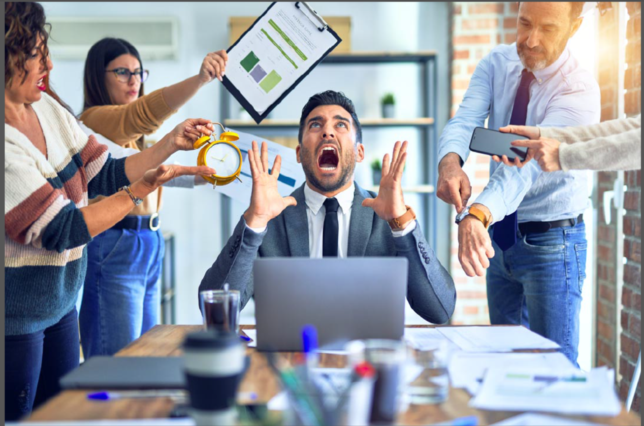 Leader overwhelmed at a desk while team members demand attention, illustrating decision pressure, urgency, and leadership stress.